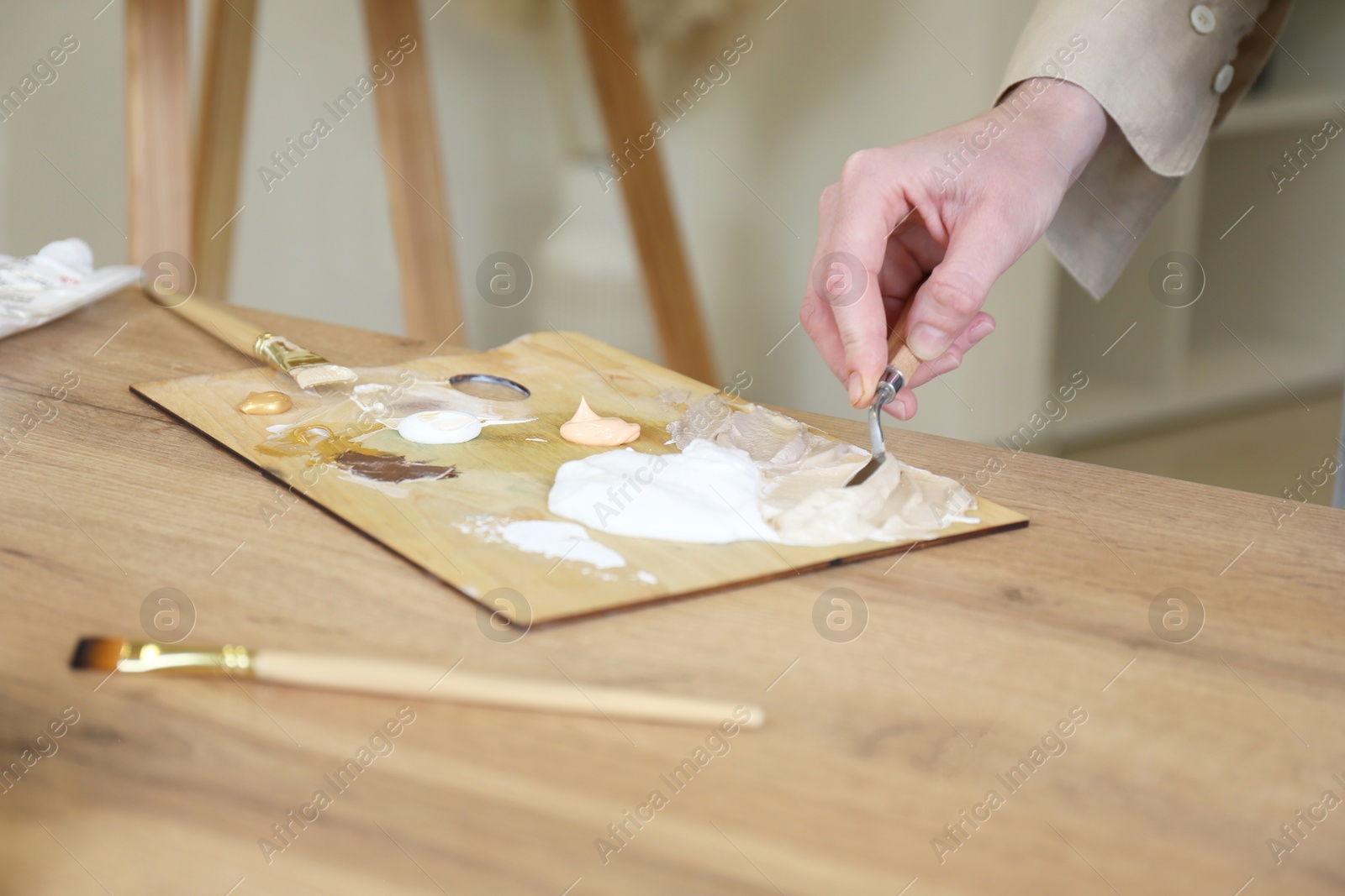 Photo of Woman with palette knife at wooden table in drawing studio, closeup