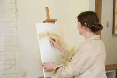 Woman drawing picture with palette knife in studio