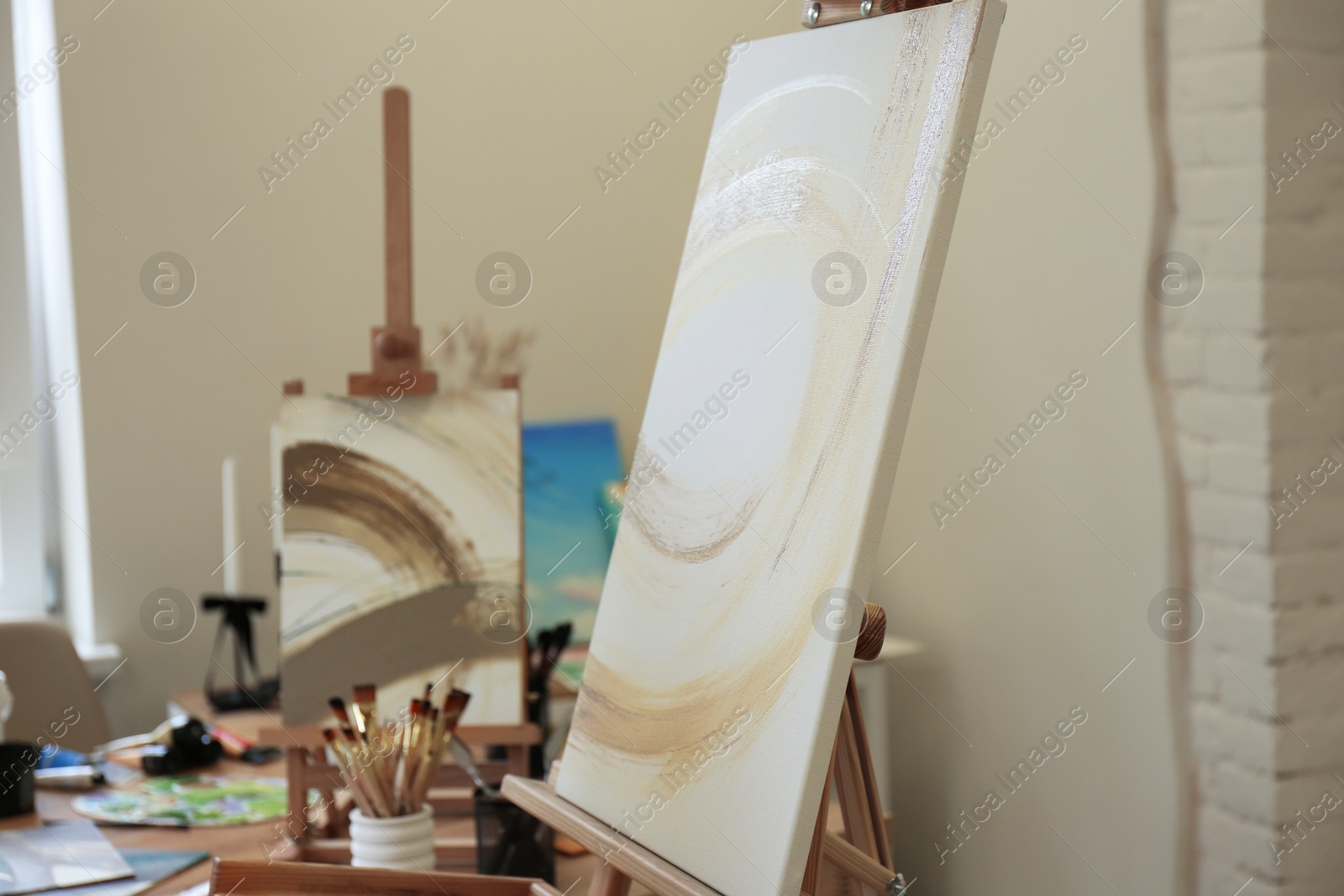 Photo of Easels with abstract pictures in drawing studio