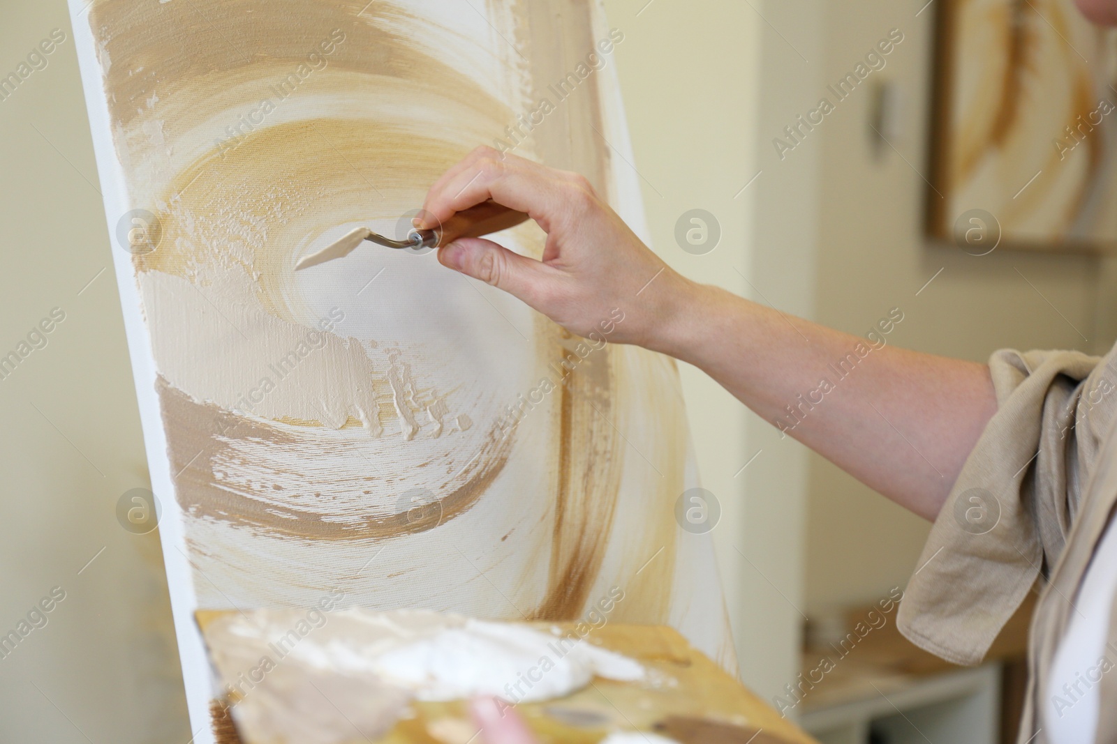 Photo of Woman with palette knife drawing picture in studio, closeup