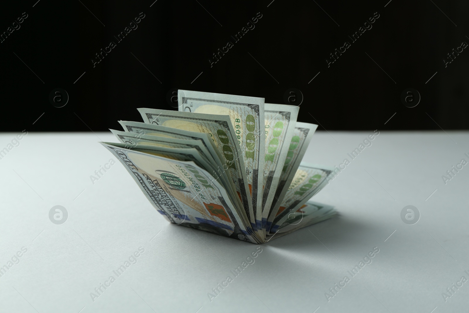 Photo of Dollar banknotes on grey table against black background