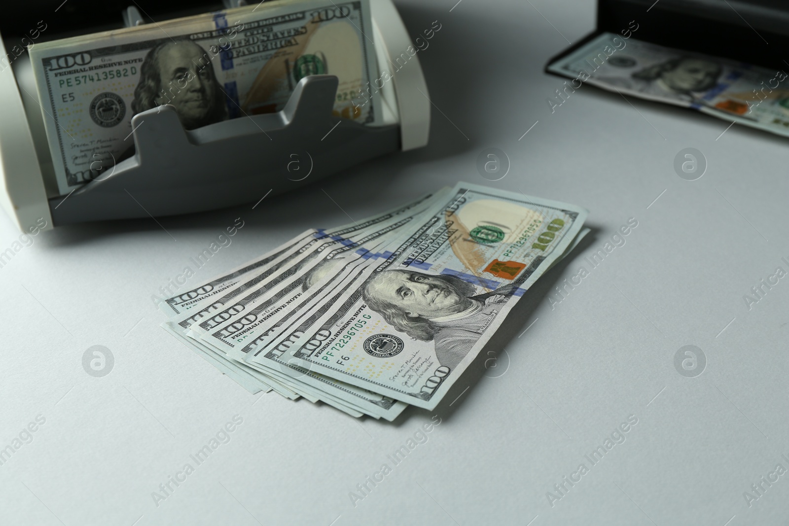 Photo of Dollar banknotes and money counter machine on light table