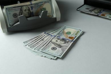 Photo of Dollar banknotes and money counter machine on light table