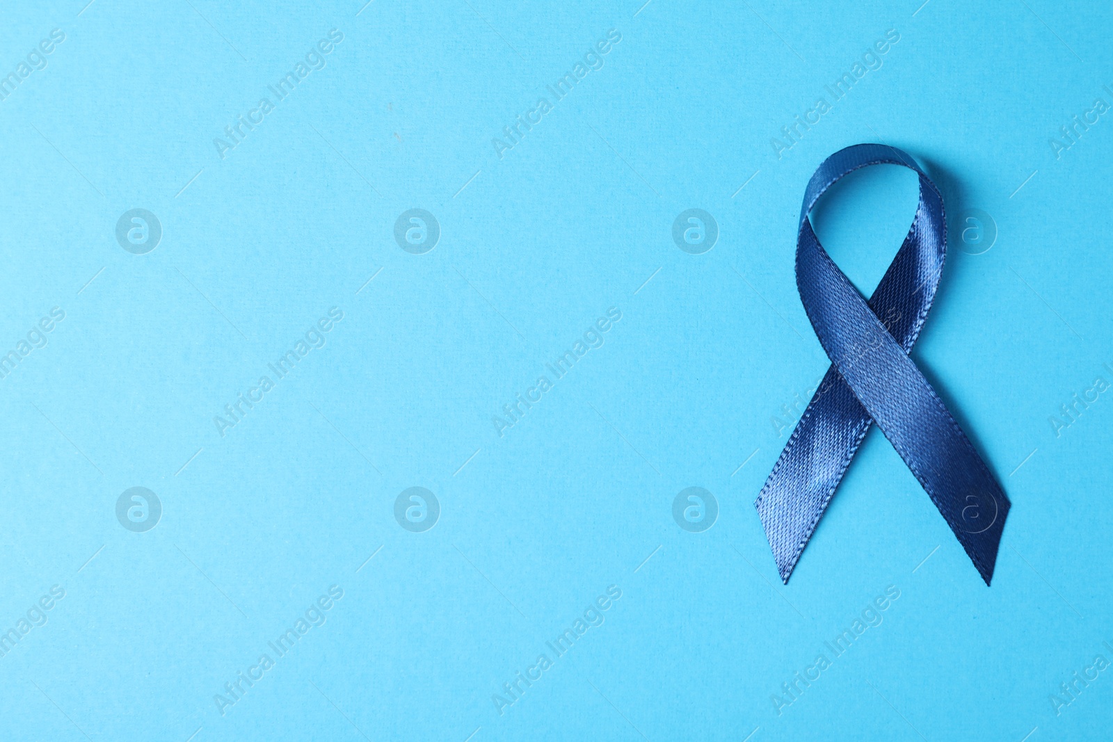 Photo of Dark blue ribbon on color background, top view with space for text. Prostate cancer awareness