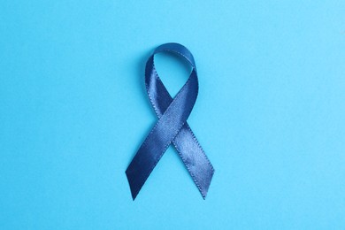 Photo of Dark blue ribbon on color background, top view. Prostate cancer awareness