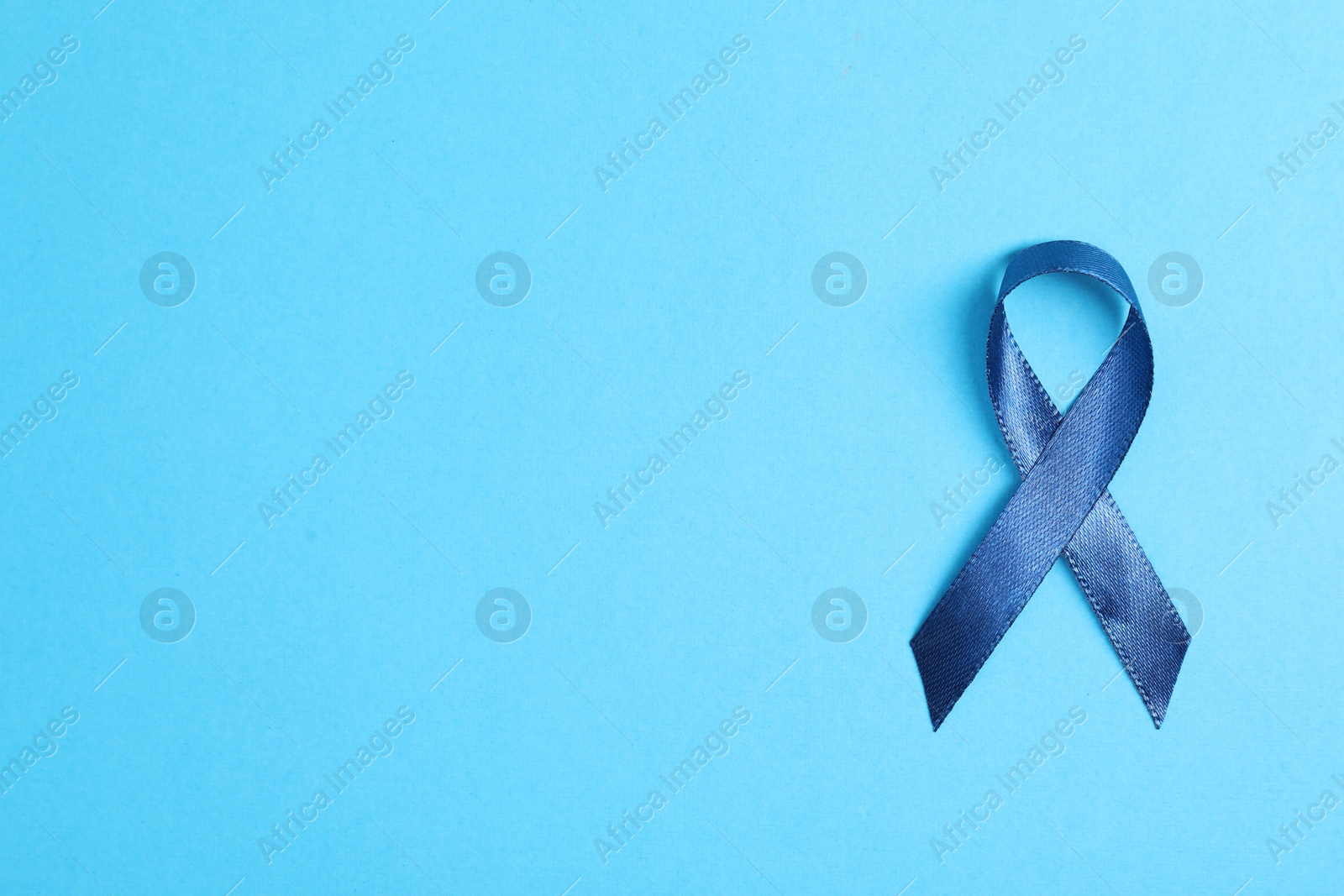 Photo of Dark blue ribbon on color background, top view with space for text. Prostate cancer awareness