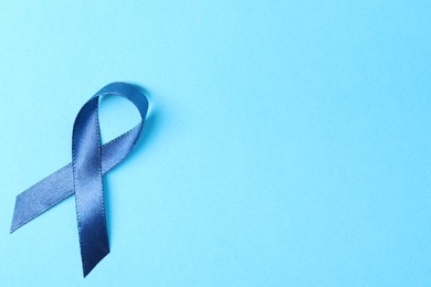 Photo of Dark blue ribbon on color background, top view with space for text. Prostate cancer awareness