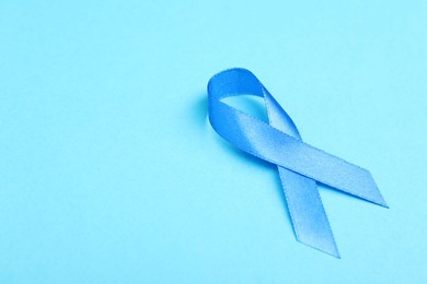 Prostate cancer awareness. Blue ribbon on color background, closeup. Space for text