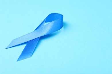 Prostate cancer awareness. Blue ribbon on color background, closeup. Space for text