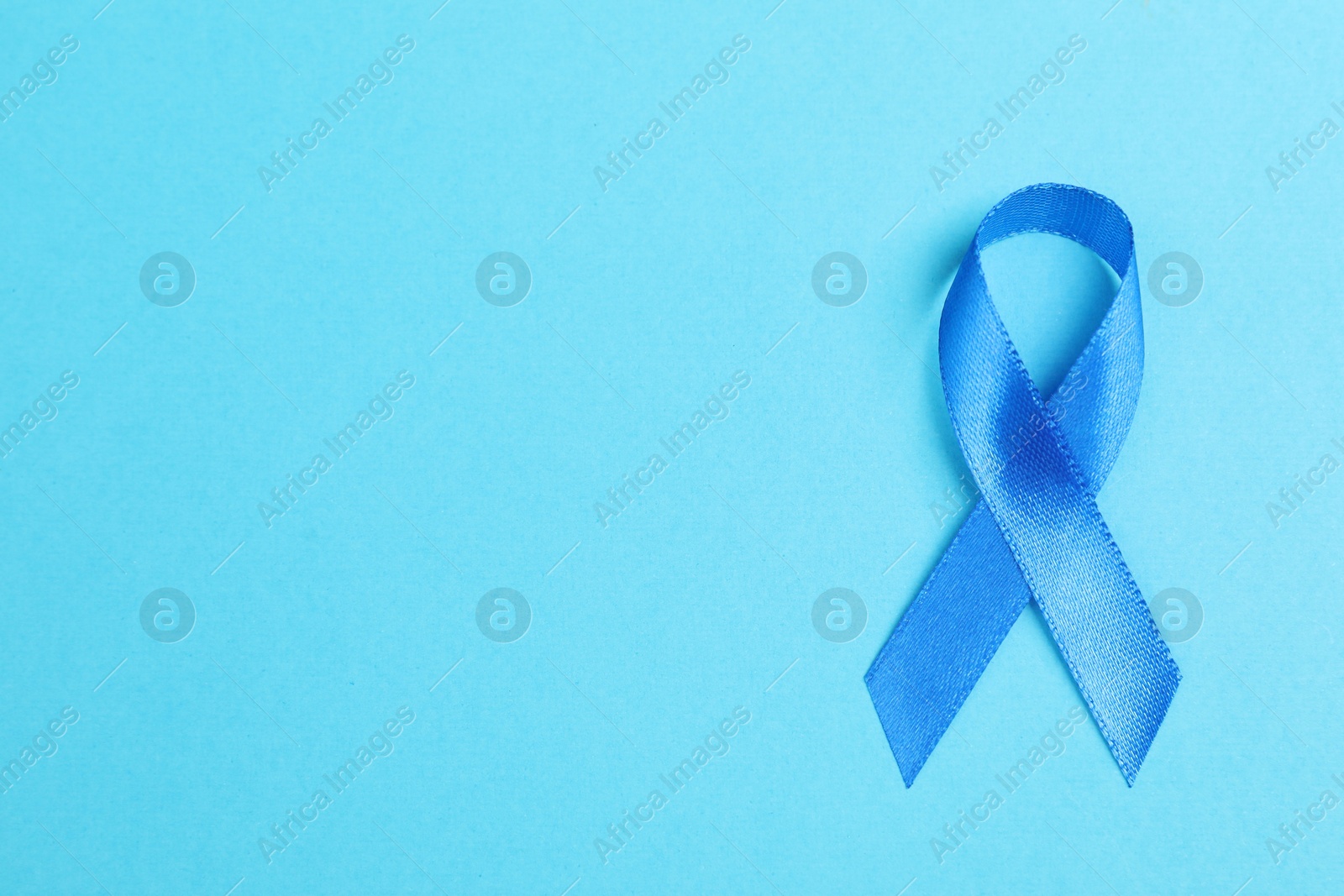 Photo of Blue ribbon on color background, top view with space for text. Prostate cancer awareness