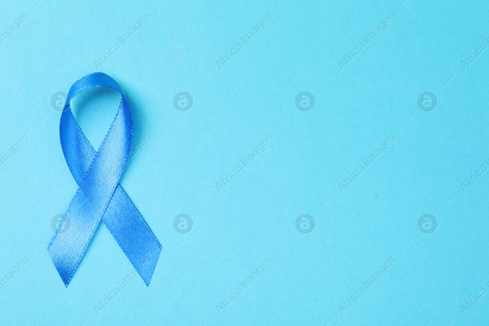 Photo of Blue ribbon on color background, top view with space for text. Prostate cancer awareness