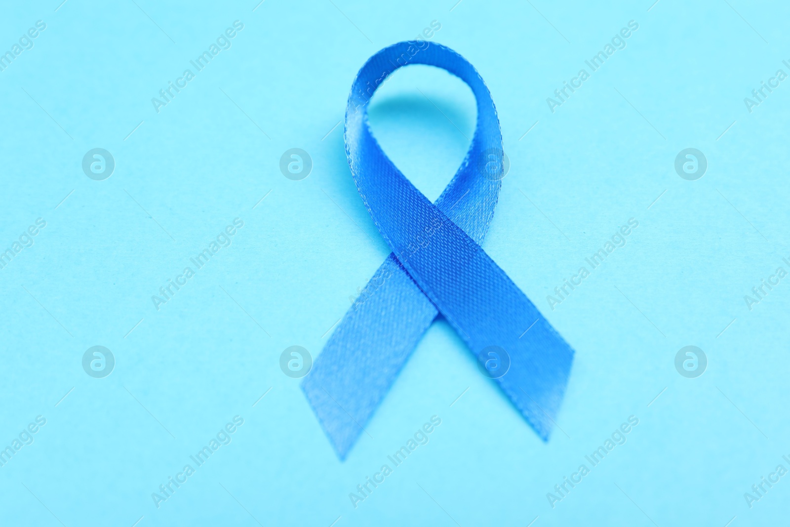 Photo of Blue ribbon on color background, closeup. Prostate cancer awareness