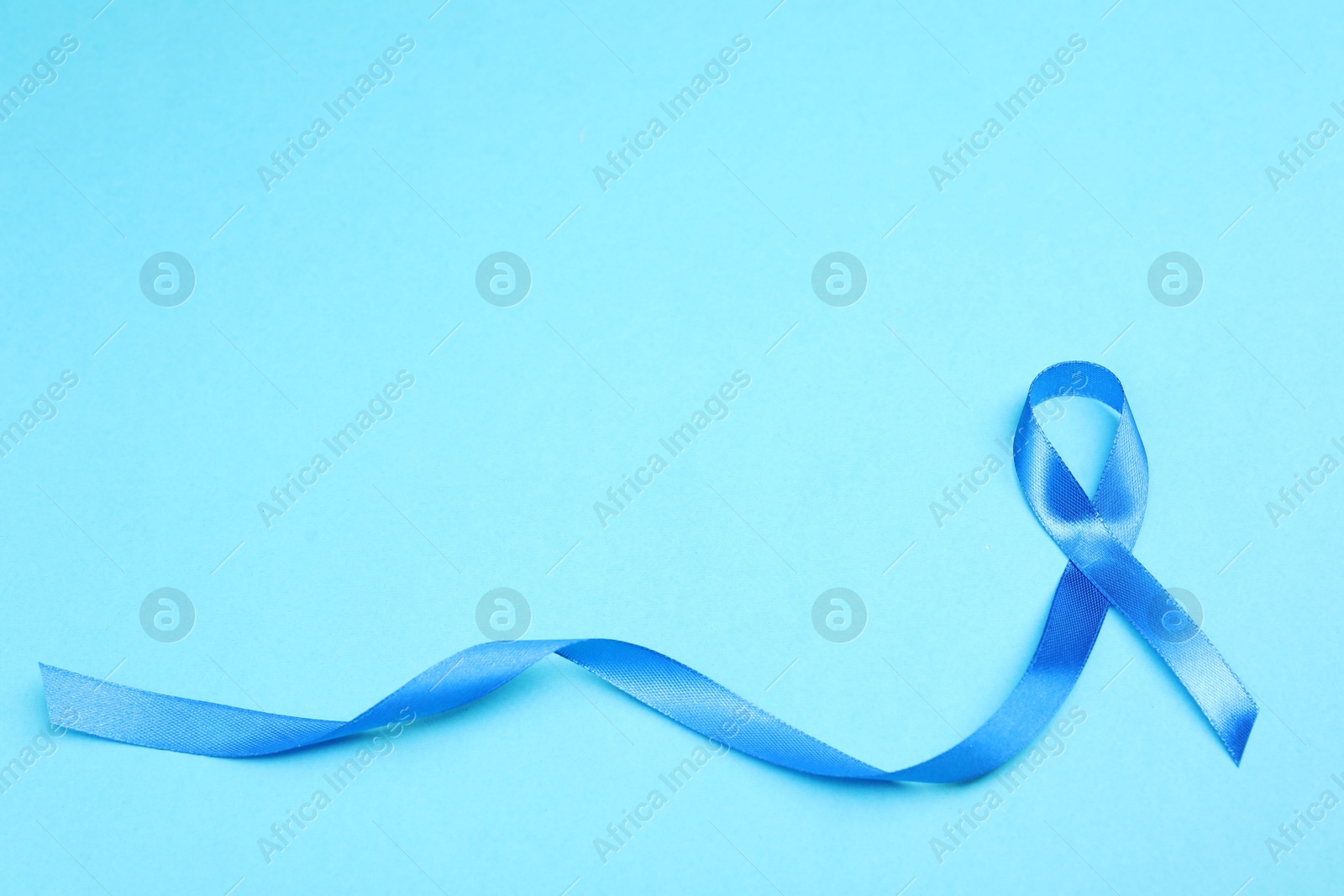 Photo of Blue ribbon on color background, top view with space for text. Prostate cancer awareness