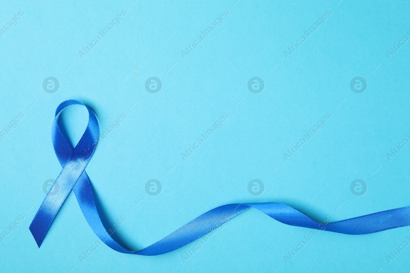 Photo of Blue ribbon on color background, top view with space for text. Prostate cancer awareness