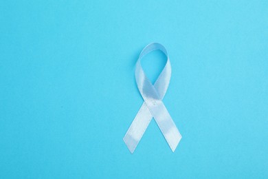 Photo of Light blue ribbon on color background, top view with space for text. Prostate cancer awareness