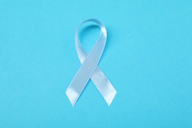 Photo of Light blue ribbon on color background, top view. Prostate cancer awareness