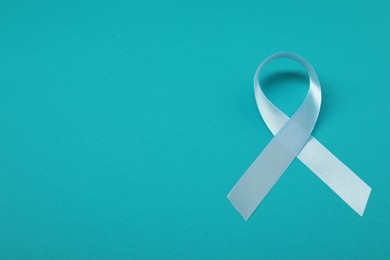 Photo of Prostate cancer awareness. Light blue ribbon on teal background, space for text