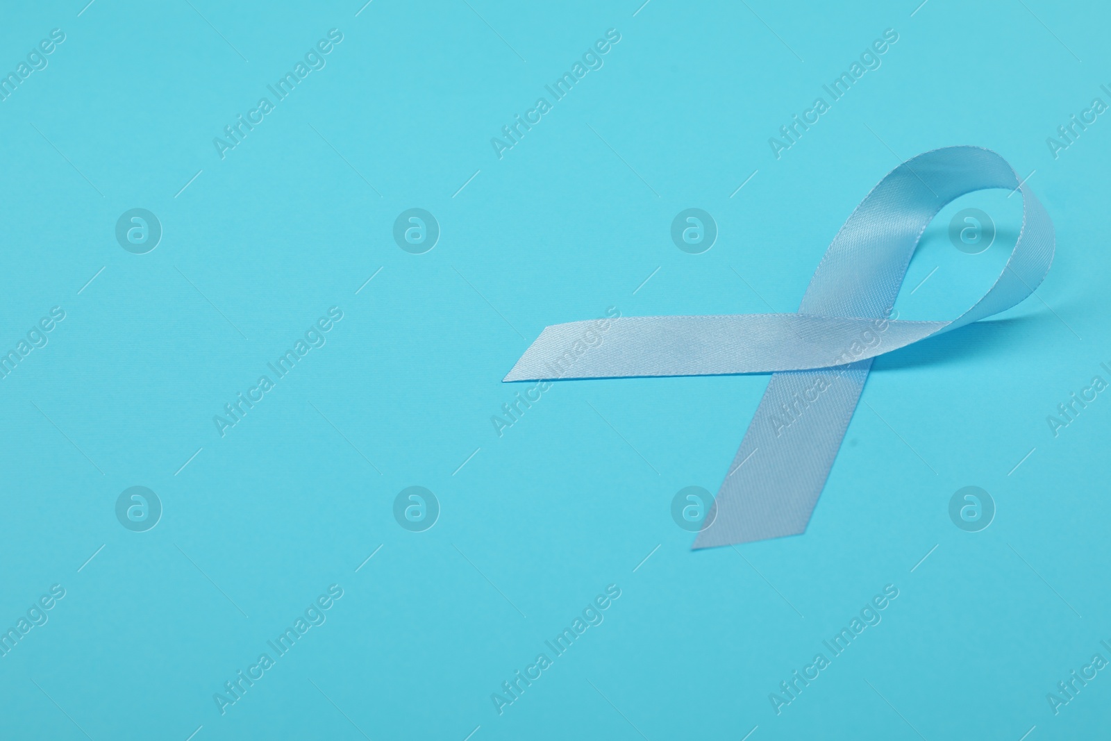 Photo of Prostate cancer awareness. Light blue ribbon on color background, space for text