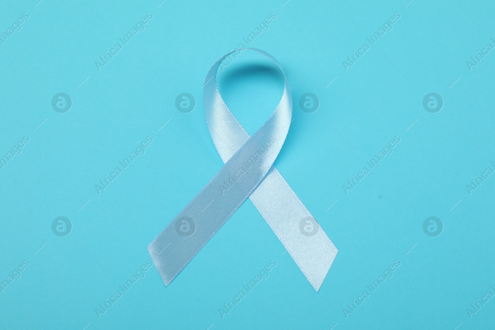 Photo of Light blue ribbon on color background, top view. Prostate cancer awareness