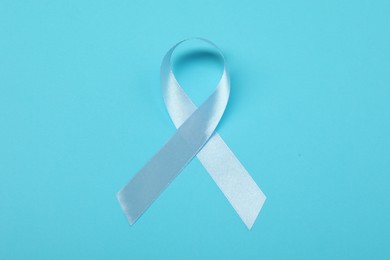 Photo of Light blue ribbon on color background, top view. Prostate cancer awareness