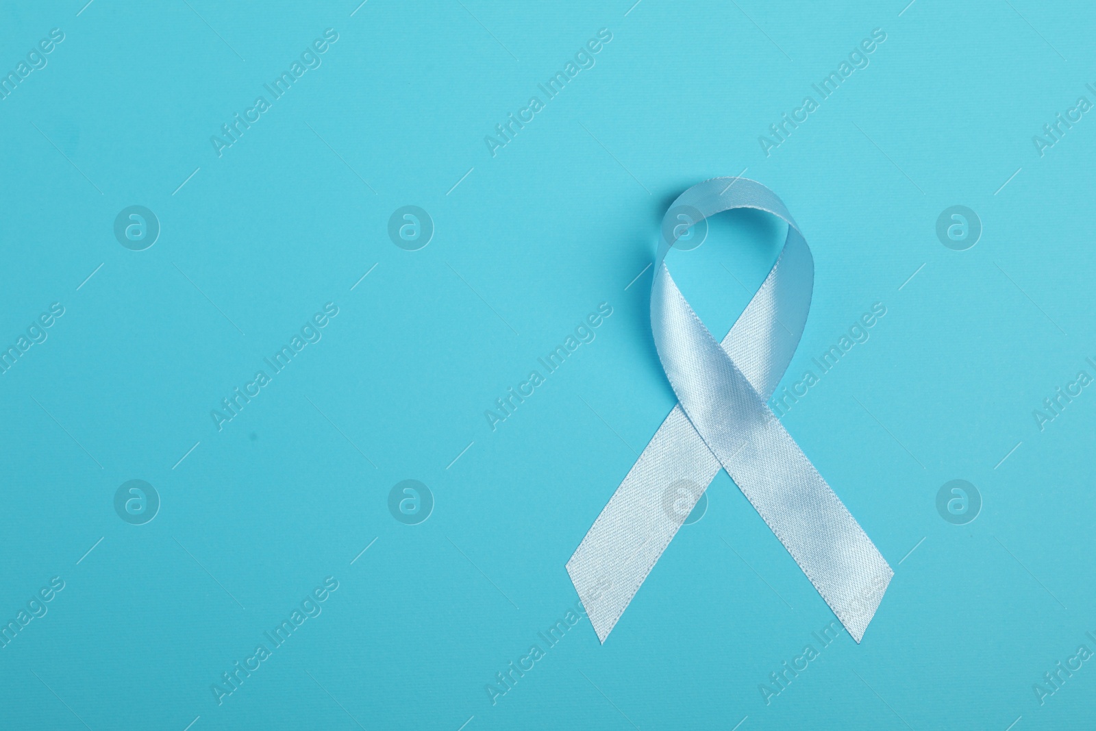 Photo of Light blue ribbon on color background, top view with space for text. Prostate cancer awareness