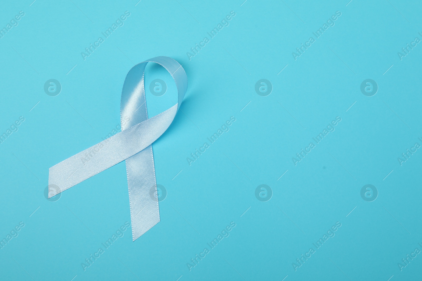 Photo of Light blue ribbon on color background, top view with space for text. Prostate cancer awareness