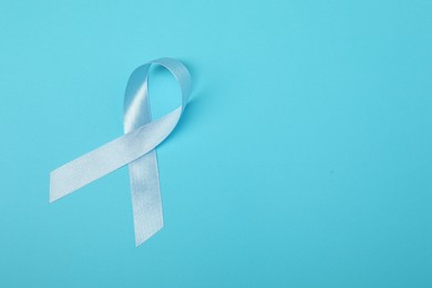 Photo of Light blue ribbon on color background, top view with space for text. Prostate cancer awareness