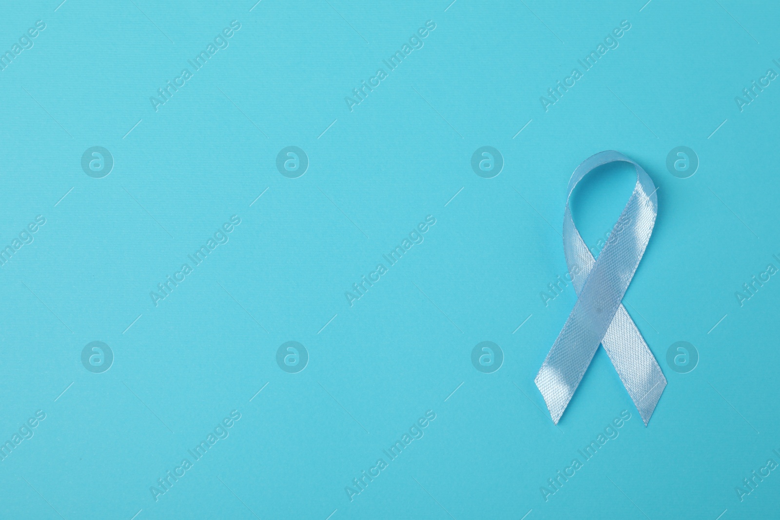 Photo of Light blue ribbon on color background, top view with space for text. Prostate cancer awareness