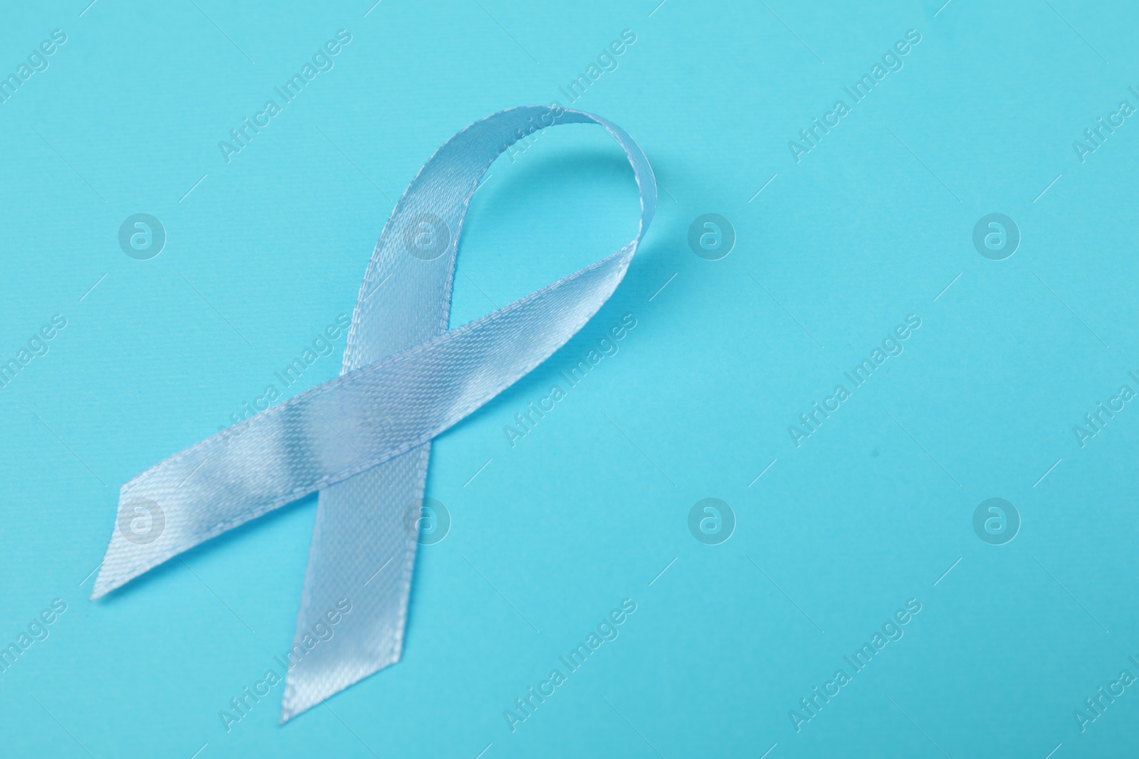 Photo of Prostate cancer awareness. Light blue ribbon on color background, closeup. Space for text