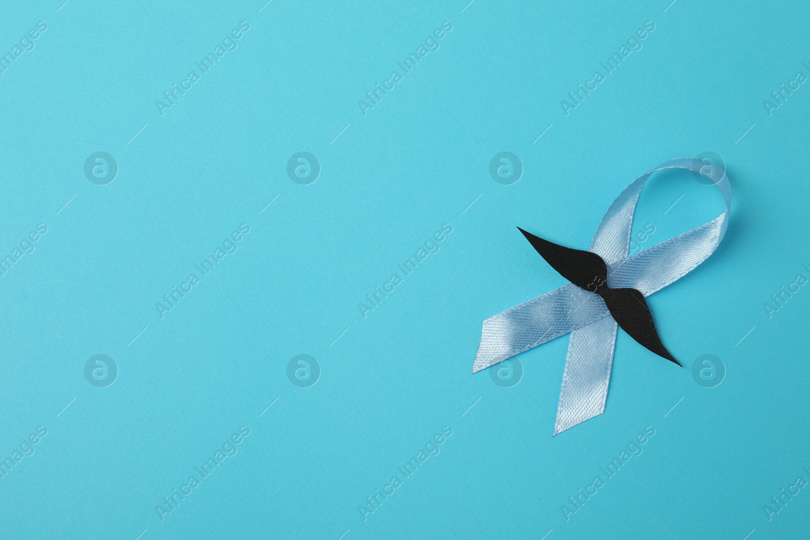 Photo of Light blue ribbon and fake mustache on color background, top view with space for text. Prostate cancer awareness