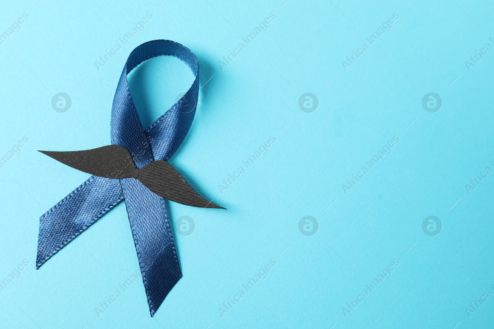 Photo of Dark blue ribbon and fake mustache on color background, top view with space for text. Prostate cancer awareness