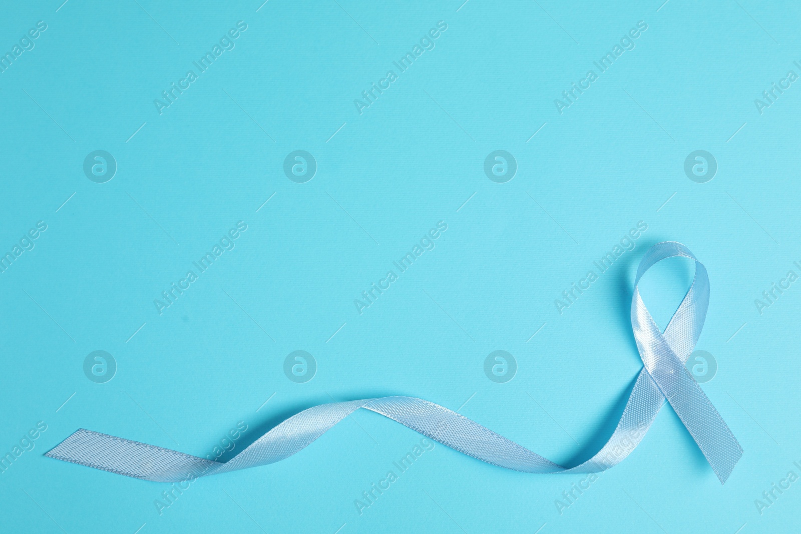 Photo of Light blue ribbon on color background, top view with space for text. Prostate cancer awareness