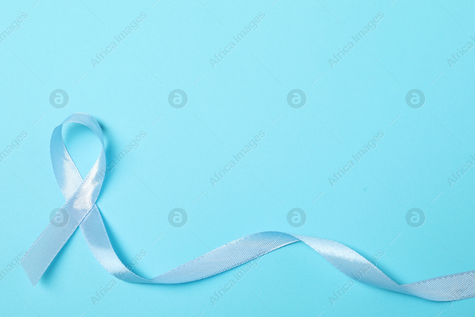 Photo of Light blue ribbon on color background, top view with space for text. Prostate cancer awareness