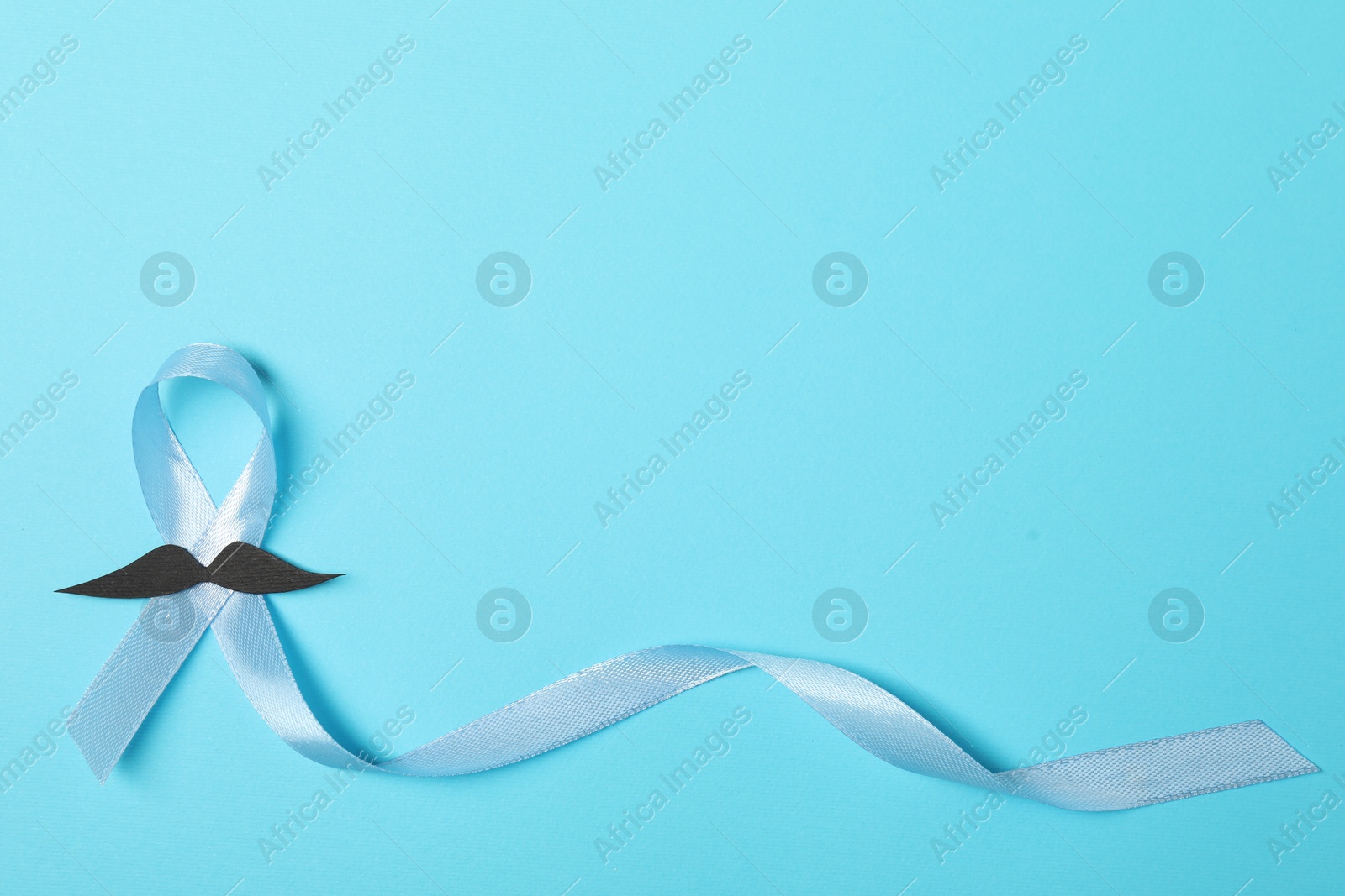 Photo of Light blue ribbon and fake mustache on color background, top view with space for text. Prostate cancer awareness