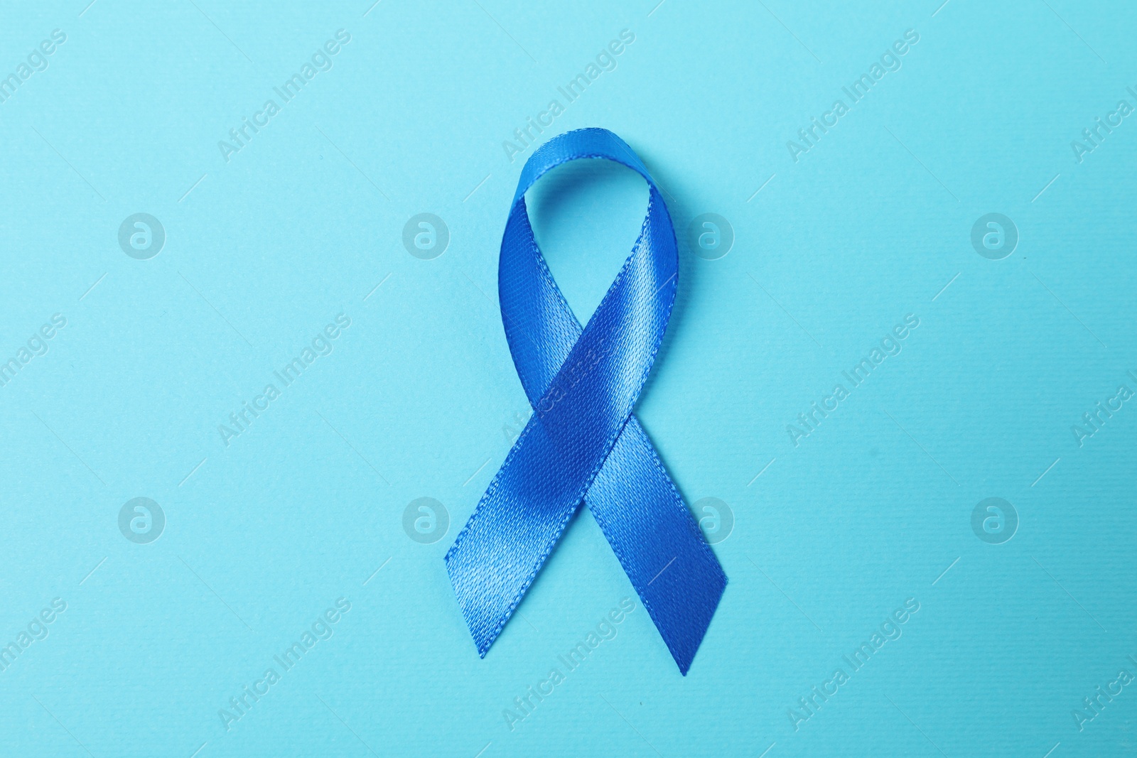 Photo of Blue ribbon on color background, top view. Prostate cancer awareness