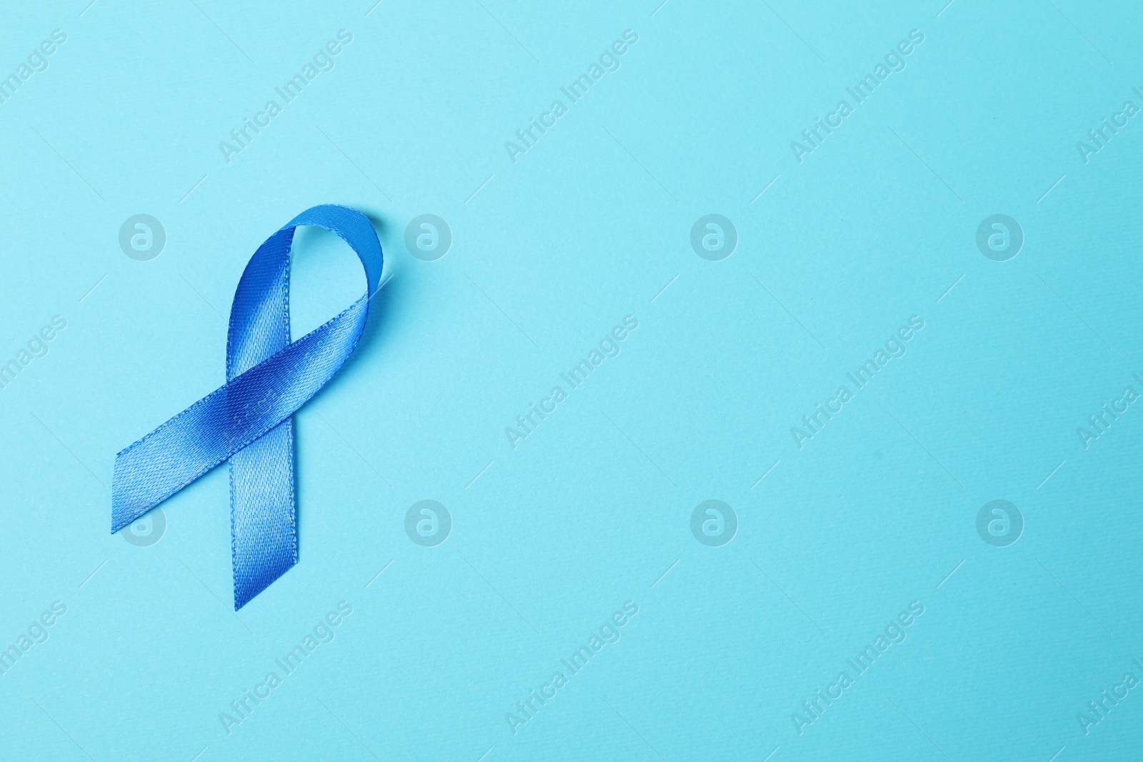 Photo of Blue ribbon on color background, top view with space for text. Prostate cancer awareness