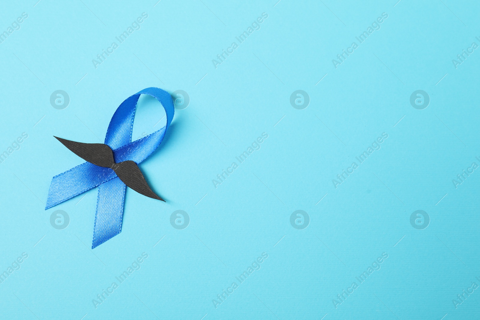 Photo of Blue ribbon and fake mustache on color background, top view with space for text. Prostate cancer awareness