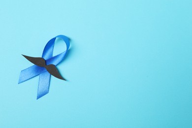 Photo of Blue ribbon and fake mustache on color background, top view with space for text. Prostate cancer awareness