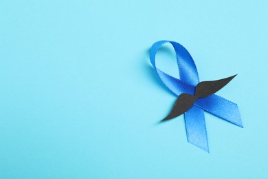 Photo of Blue ribbon and fake mustache on color background, top view. Prostate cancer awareness