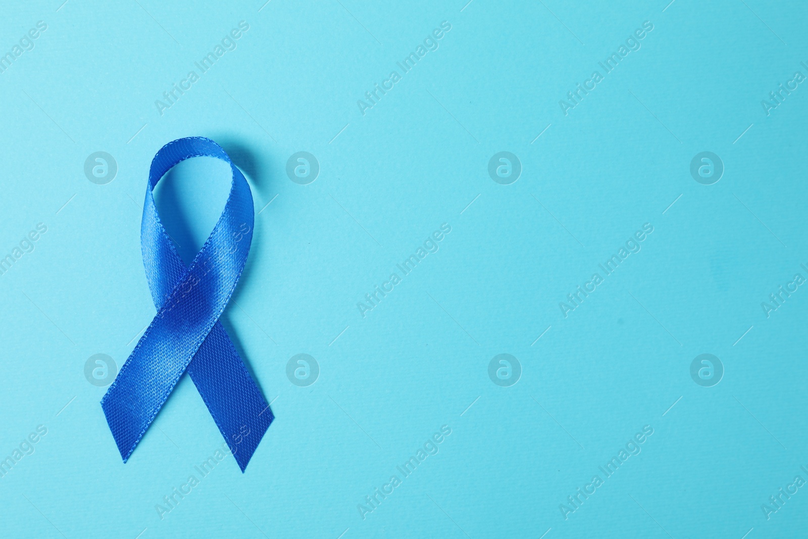 Photo of Blue ribbon on color background, top view with space for text. Prostate cancer awareness