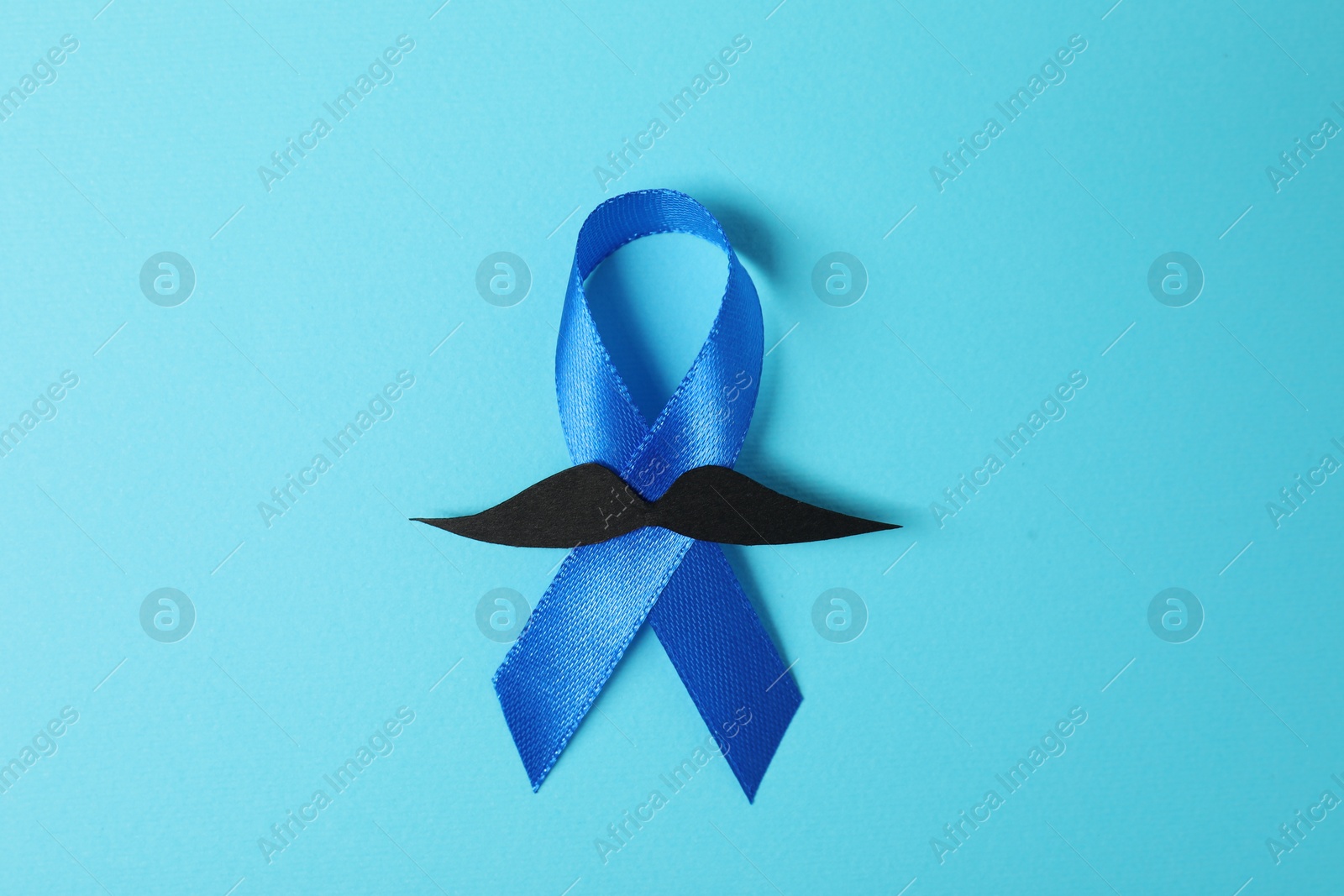 Photo of Blue ribbon and fake mustache on color background, top view. Prostate cancer awareness