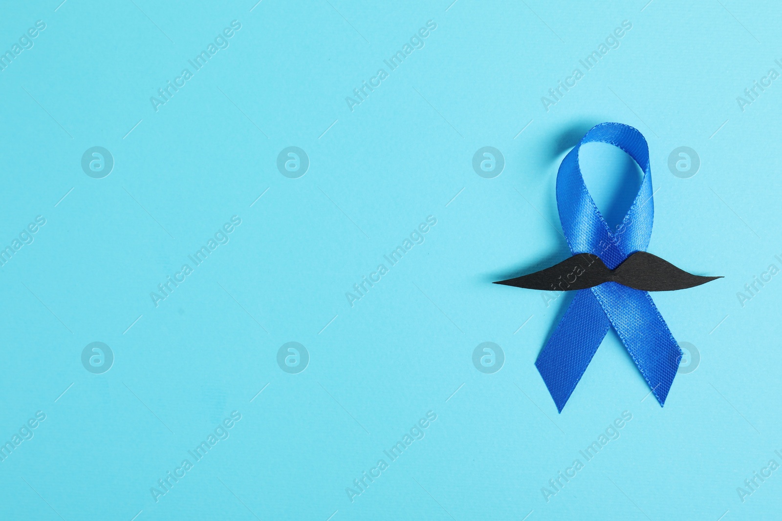 Photo of Blue ribbon and fake mustache on color background, top view with space for text. Prostate cancer awareness