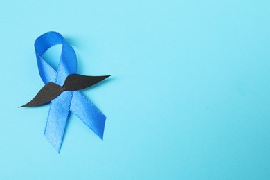 Photo of Blue ribbon and fake mustache on color background, top view with space for text. Prostate cancer awareness