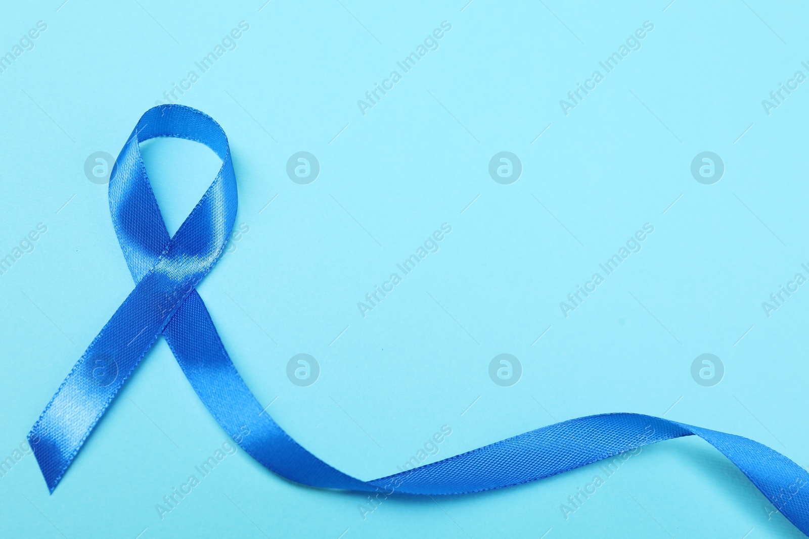 Photo of Blue ribbon on color background, top view with space for text. Prostate cancer awareness