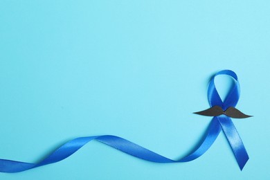 Photo of Blue ribbon and fake mustache on color background, top view with space for text. Prostate cancer awareness