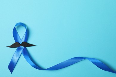 Blue ribbon and fake mustache on color background, top view with space for text. Prostate cancer awareness