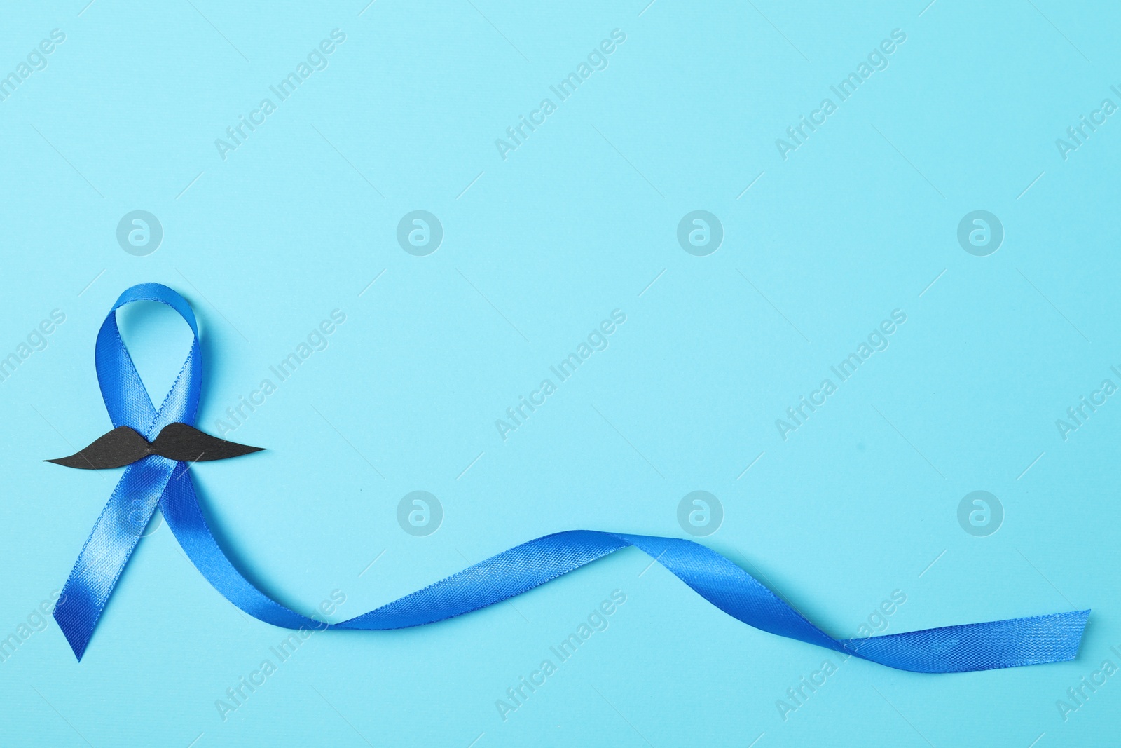 Photo of Blue ribbon and fake mustache on color background, top view with space for text. Prostate cancer awareness