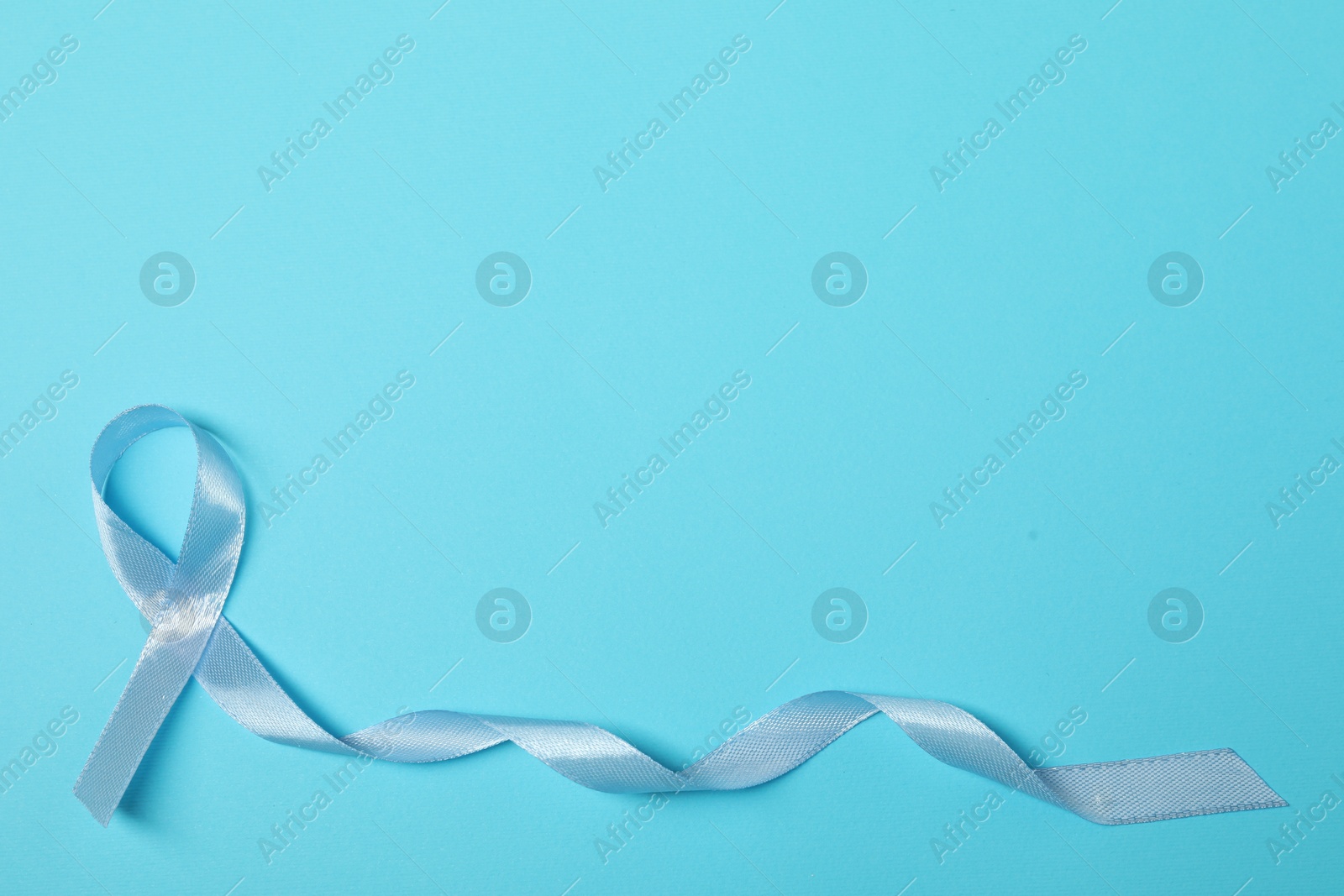 Photo of Light blue ribbon on color background, top view with space for text. Prostate cancer awareness