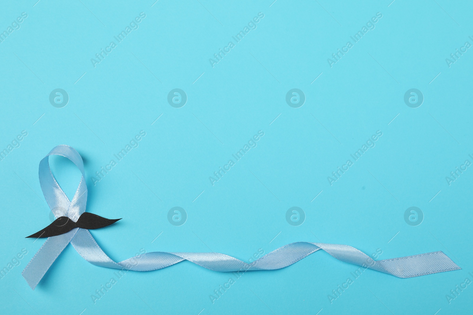 Photo of Light blue ribbon and fake mustache on color background, top view with space for text. Prostate cancer awareness