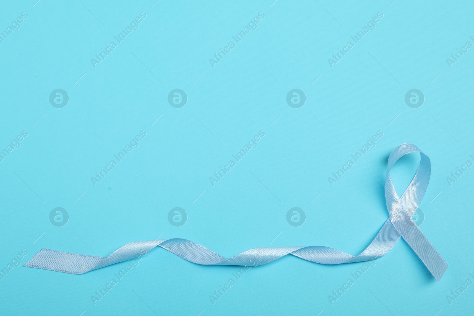 Photo of Light blue ribbon on color background, top view with space for text. Prostate cancer awareness